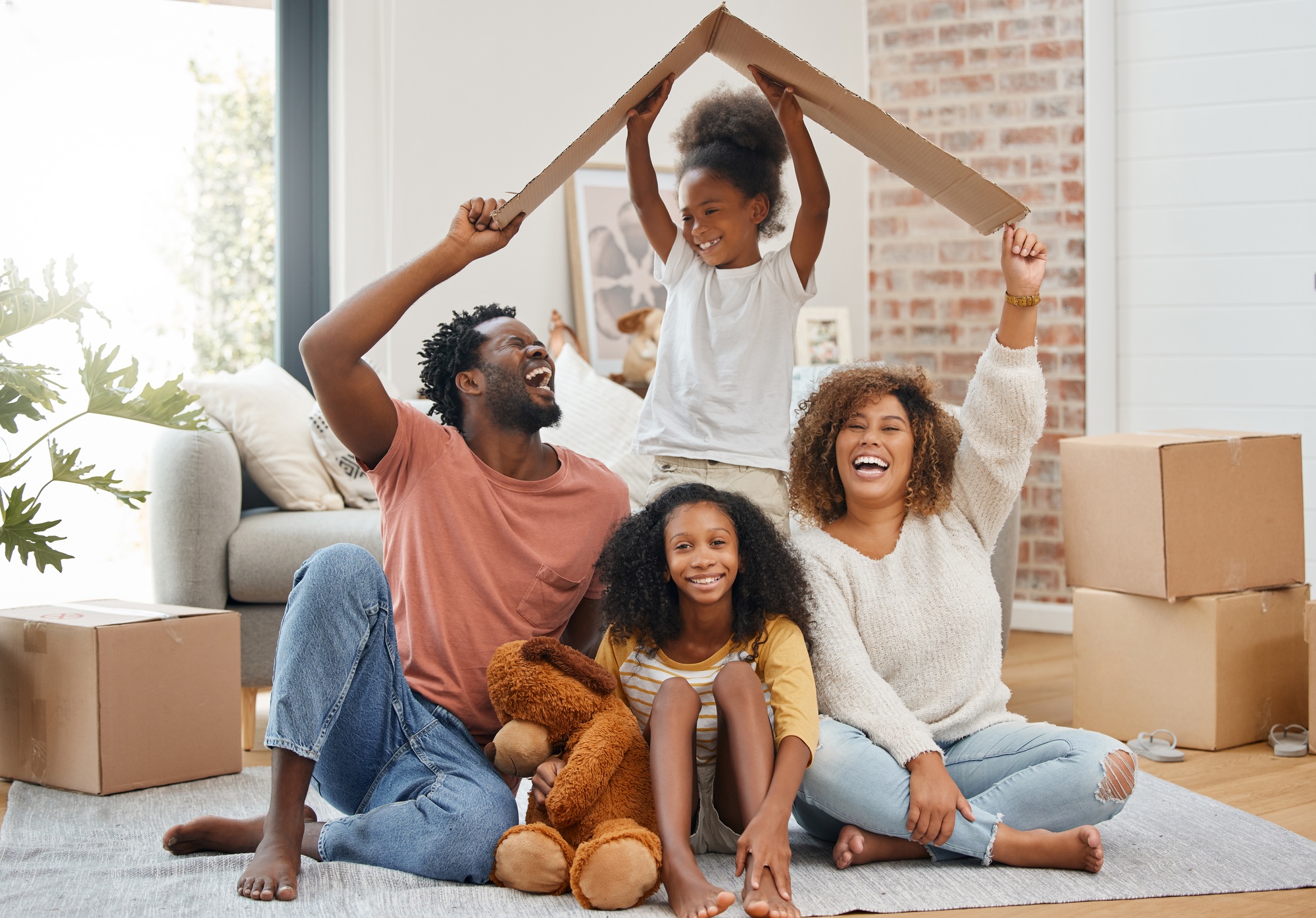 A family affair. Shot of a young family holding up a cardboard box to form a roof at home.